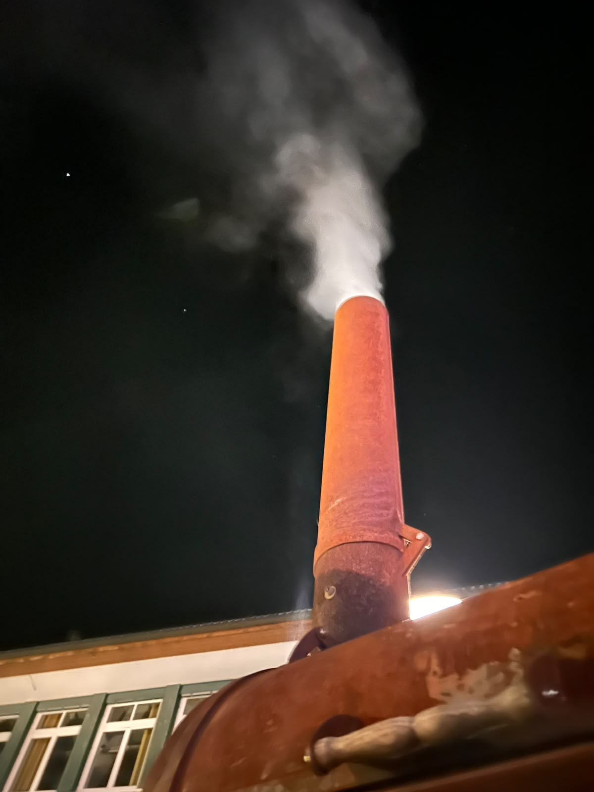 Rauch steigt nachts aus dem Schornstein unserer Grilllok